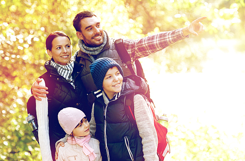 adventure, travel, tourism, hike and people concept - happy family walking with backpacks in woods