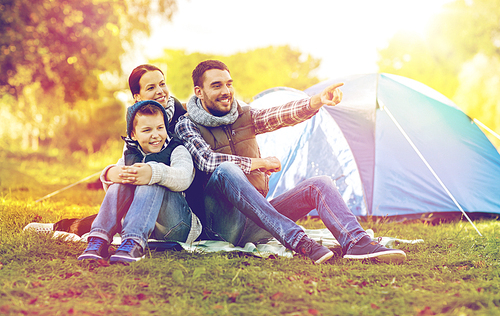 tourism, hike and travel concept - happy family over tent at camp site pointing finger to something