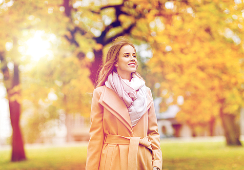 season and people concept - beautiful happy young woman walking in autumn park