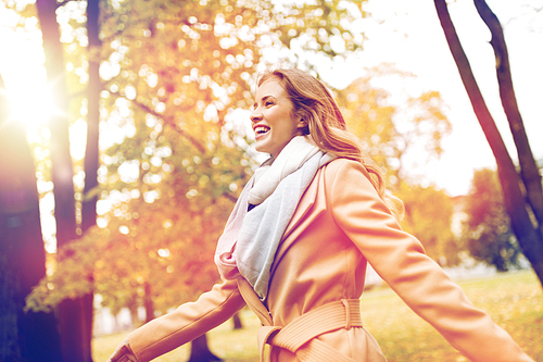 season and people concept - beautiful happy young woman walking in autumn park