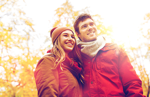 love, relationships, season and people concept - happy young couple walking in autumn park