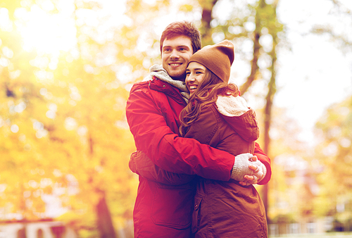 love, relationships, season and people concept - happy young couple hugging in autumn park