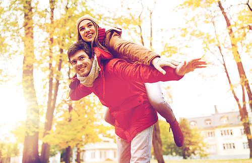 love, relationships, season and people concept - happy young couple having fun in autumn park