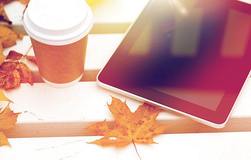 season, technology and advertisement concept - close up of tablet pc computer and coffee paper cup on bench in autumn park