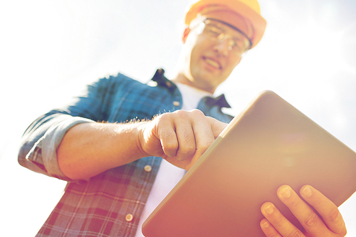 business, building, industry, technology and people concept - close up of smiling builder in hardhat with tablet pc computer outdoors