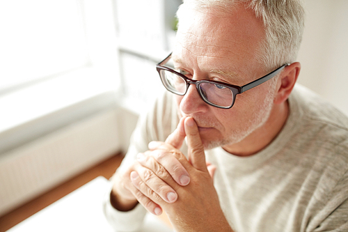 old age, problem and people concept - close up of senior man in glasses thinking