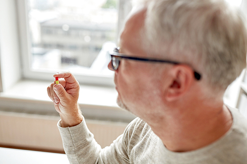 age, medicine, healthcare and people concept - close up of senior man hand with pill