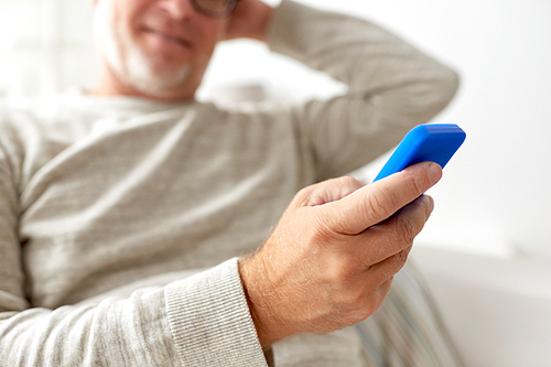 technology, people, lifestyle and communication concept - close up of happy senior man dialing phone number and texting on smartphone at home