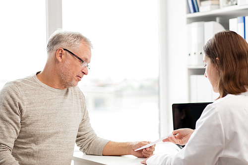 medicine, age, health care and people concept - senior man and doctor with prescription meeting in medical office at hospital