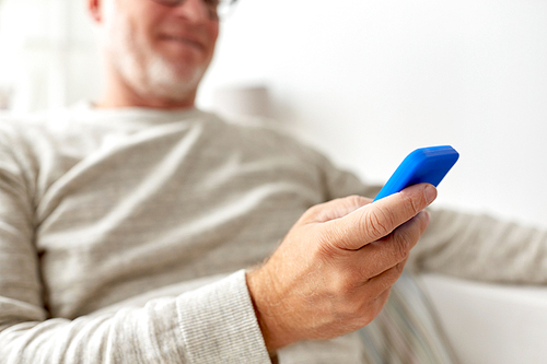 technology, people, lifestyle and communication concept - close up of happy senior man dialing phone number and texting on smartphone at home