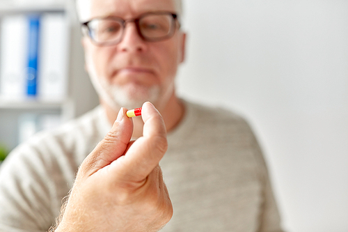 age, medicine, healthcare and people concept - close up of senior man hand with pill