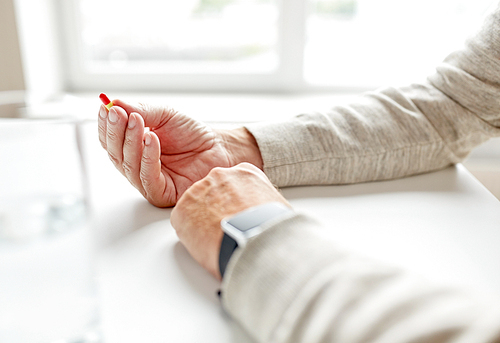 age, medicine, healthcare and people concept - close up of senior man hands with pill