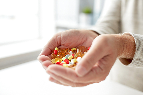 old age, medicine, drugs, healthcare and people concept - close up of senior man hands holding pills