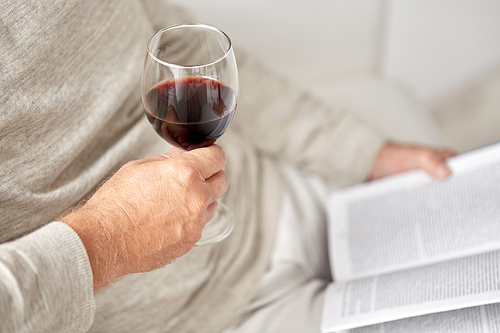 old age, alcohol, leisure and people concept - close up of senior man with red wine glass and book