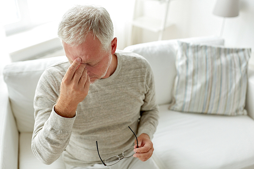 healthcare, pain, stress, age and people concept - senior man suffering from headache at home