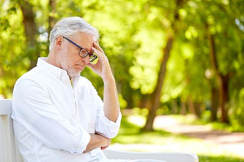 old age, retirement and people concept - thoughtful senior man in glasses sitting on bench at summer park