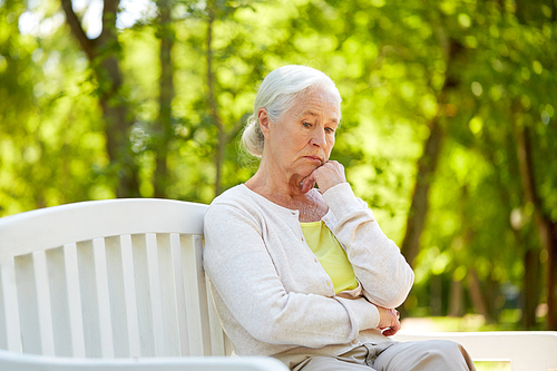 old age, retirement and people concept - sad senior woman in glasses sitting on bench at summer park