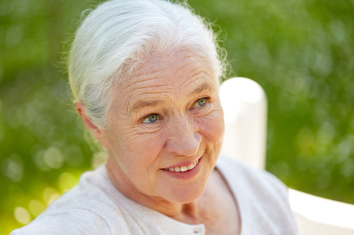 old age, retirement and people concept - close up of happy senior woman in glasses sitting on bench at summer park