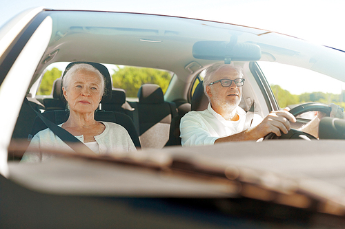 road trip, travel and old people concept - happy senior couple driving in car