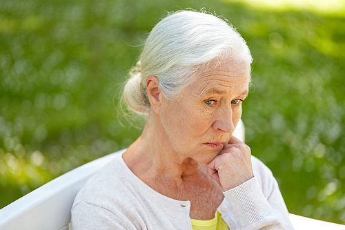 old age, retirement and people concept - sad senior woman in glasses sitting on bench at summer park