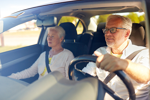 road trip, travel and old people concept - happy senior couple driving in car