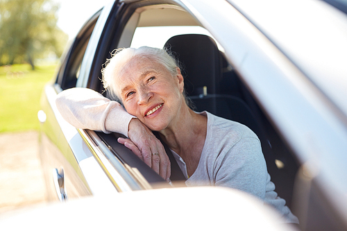 road trip, travel and old people concept - happy senior woman driving in car with open window