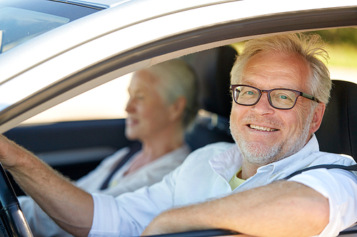 road trip, travel and old people concept - happy senior couple driving in car