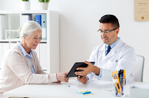 medicine, age, healthcare and people concept - smiling senior woman and doctor with tablet pc computer meeting at hospital