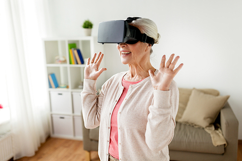 technology, augmented reality, entertainment and people concept - senior woman with virtual headset or 3d glasses playing videogame at home