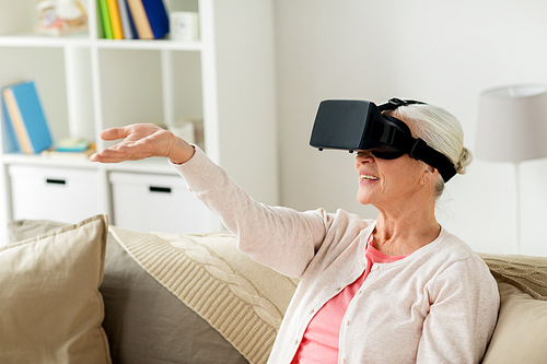 technology, augmented reality, entertainment and people concept - senior woman with virtual headset or 3d glasses playing videogame at home