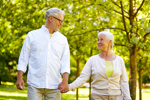 old age, retirement and people concept - happy senior couple holding hands and walking at summer park