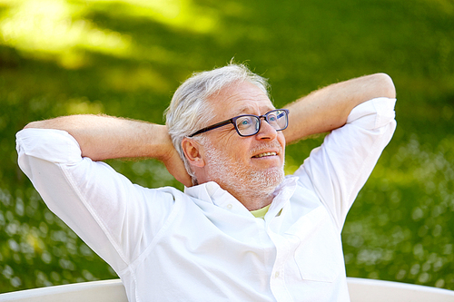 old age, retirement and people concept - happy senior man in glasses sitting and relaxing outdoors