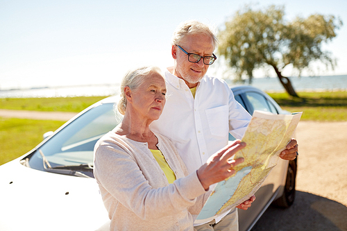 road trip, travel and old people concept - senior couple at car looking for location on map in summer