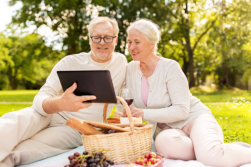 old age, holidays, leisure and people concept - happy senior couple with picnic basket sitting on blanket at summer park