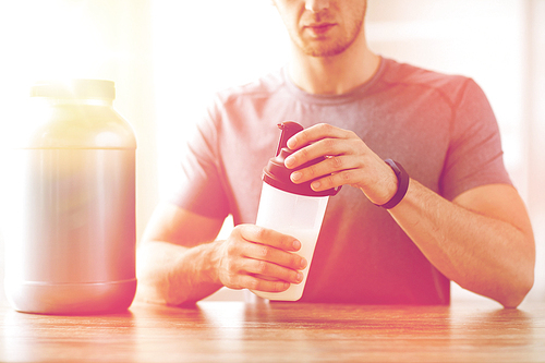 sport, fitness, healthy lifestyle and people concept - close up of man in fitness bracelet with jar and bottle preparing protein shake