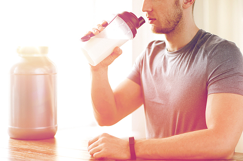 sport, fitness, healthy lifestyle and people concept - close up of man in fitness bracelet with jar and bottle drinking protein shake