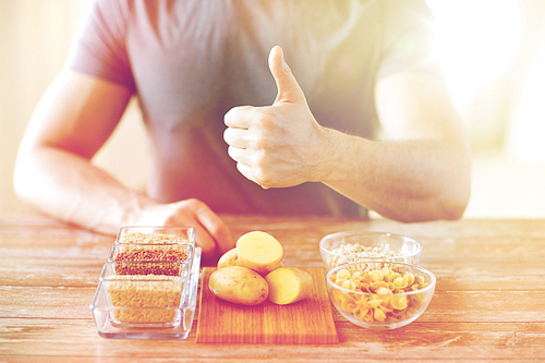 healthy eating, , gesture and people concept - close up of male hands showing thumbs up with carbohydrate food on table