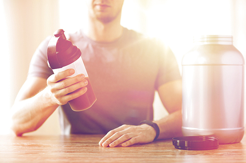 sport, fitness, healthy lifestyle and people concept - close up of man in fitness bracelet with jar and bottle preparing protein shake