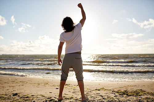 people, success, achievement and power concept - man with rised fist on beach