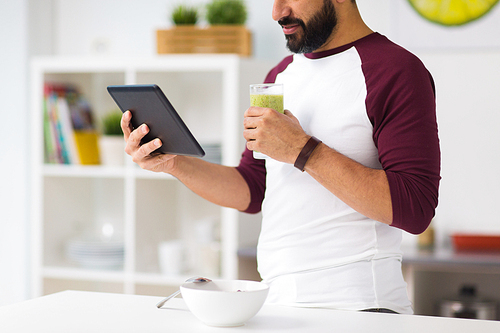 healthy eating, people, technology and diet concept - man with tablet pc computer and smoothie having breakfast at home kitchen