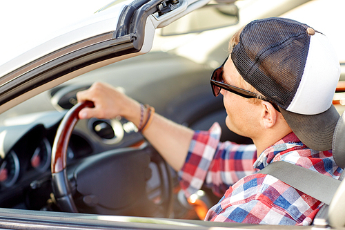 summer holidays, travel, road trip and people concept - happy young man in sunglasses and cap driving convertible car
