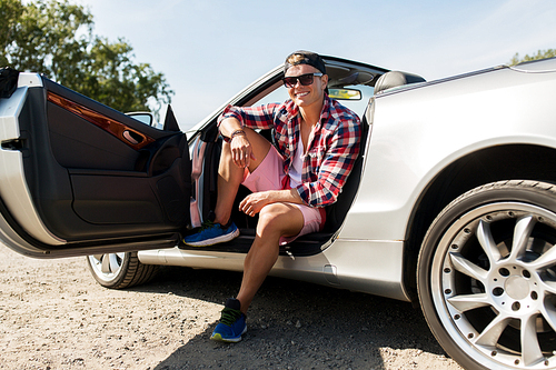 summer holidays, travel, road trip and people concept - happy young man sitting in convertible car