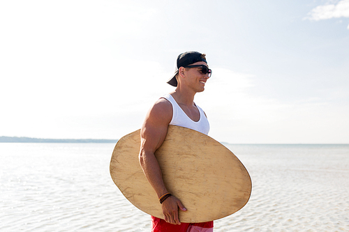 skimboarding, water sport and people concept - happy smiling young man with skimboard on summer beach