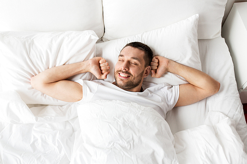people, bedtime and rest concept - man lying in bed at home