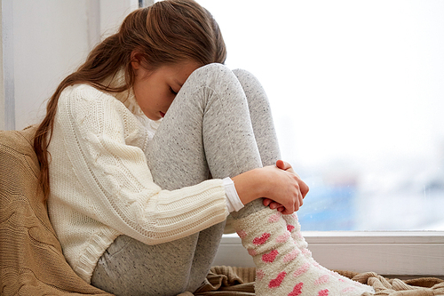 childhood, sadness and people concept - beautiful sad girl at home