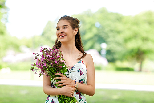 people, leisure and lifestyle concept - happy smiling young woman with flowers in summer park