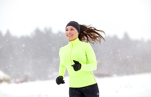 fitness, sport, people, season and healthy lifestyle concept - happy woman running along snow covered winter road