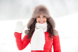 people, season and leisure concept - happy woman in winter fur hat waving hand outdoors
