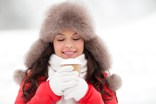 people, hot drinks and leisure concept - happy woman in winter fur with coffee cup hat outdoors