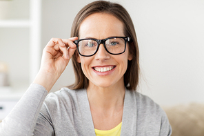 people and vision concept - happy smiling middle aged woman in glasses at home